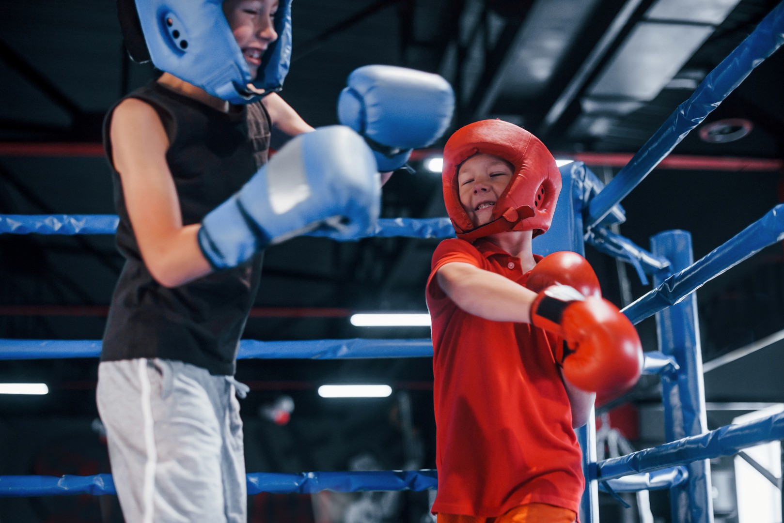 Two boys in protective equipment have sparring and fighting on the boxing ring.