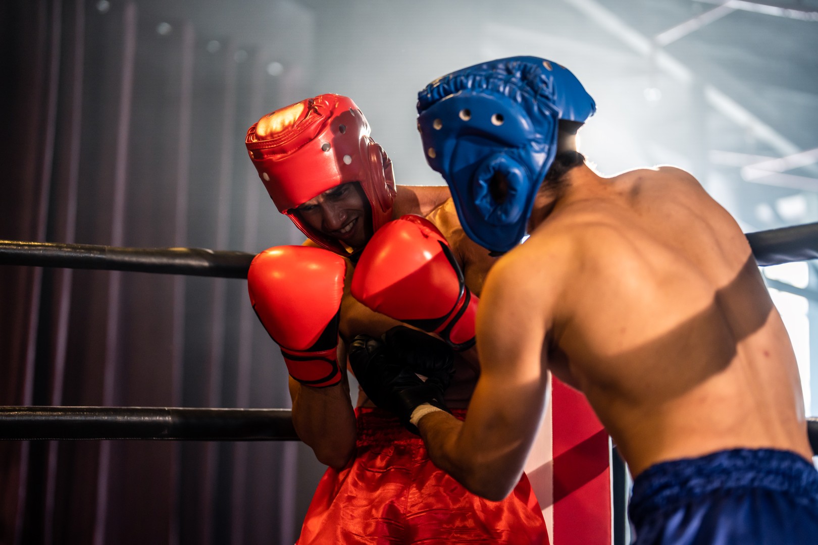 Two young professional boxer having a competition tournament on stage. Attractive male athlete fighters muscular shirtless punches and hitting competitor enjoy boxing exercise in the ring at stadium.