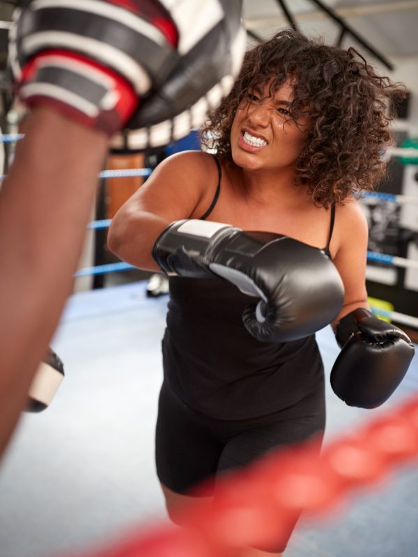 Male Personal Trainer Sparring With Female Boxer In Gym Using Training Gloves